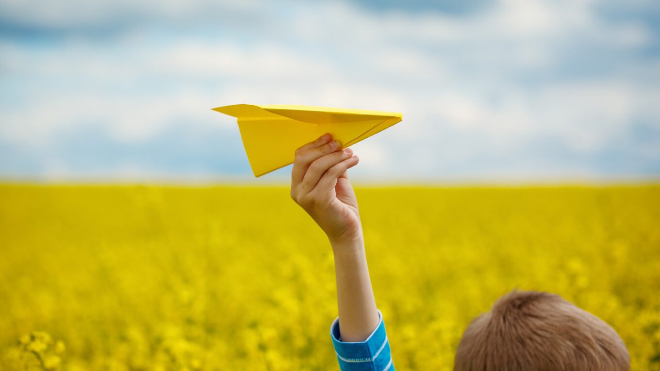 Child playing with a paper aeroplane